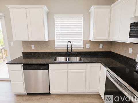 A kitchen with white cabinets and a black countertop.