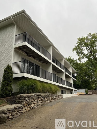A white building with a balcony and a stone wall in front.
