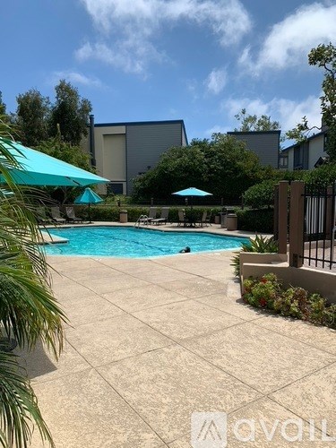 A pool surrounded by a concrete patio and a metal fence.