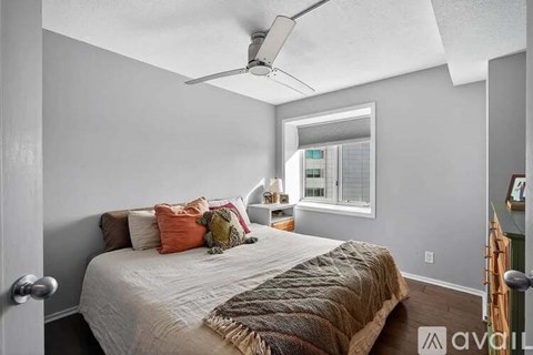 A bedroom with a bed, pillows, a ceiling fan, and a window.