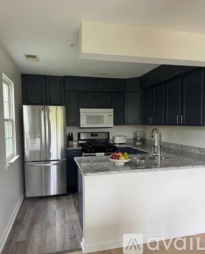A kitchen with black cabinets and a stainless steel refrigerator.
