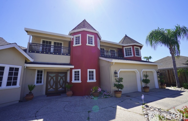 A large house with a red and white exterior and a balcony on the second floor.