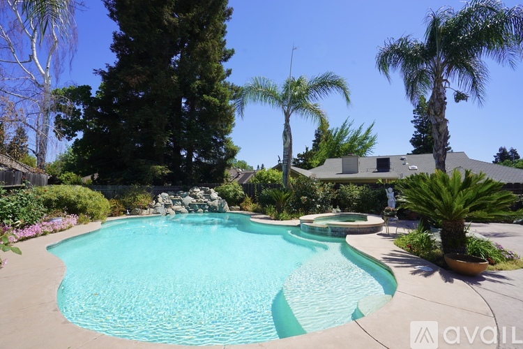 A pool surrounded by palm trees and a house in the background.