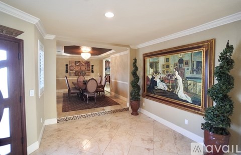 A large room with a painting on the wall and a dining table with chairs.