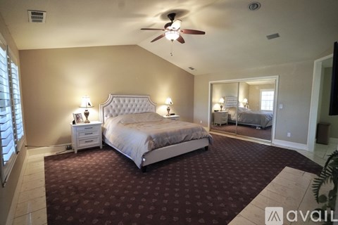 A bedroom with a large bed and a ceiling fan.