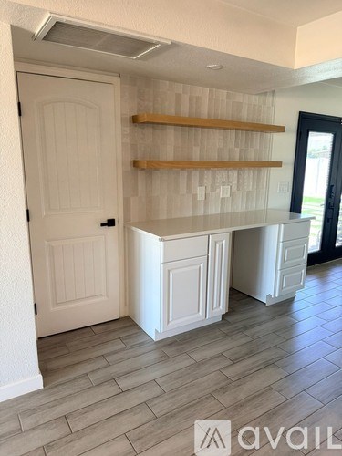 A kitchen with a white door and a white cabinet with a counter.