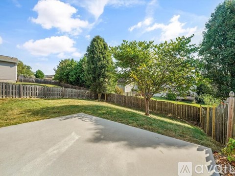 A driveway leads to a house with a fence and trees.