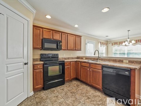 A kitchen with brown cabinets and black appliances.
