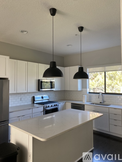 A kitchen with a white countertop and black pendant lights.