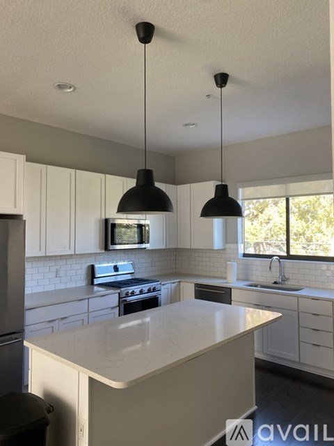 A kitchen with a white countertop and black pendant lights.