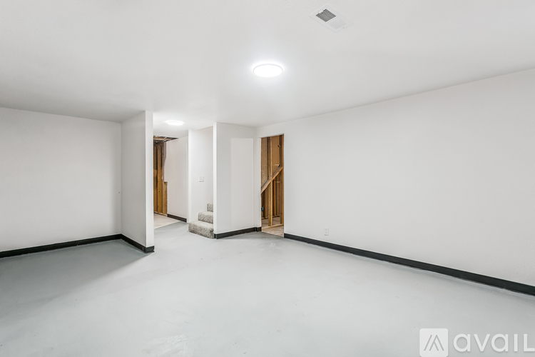 A spacious empty room with white walls and a white floor.