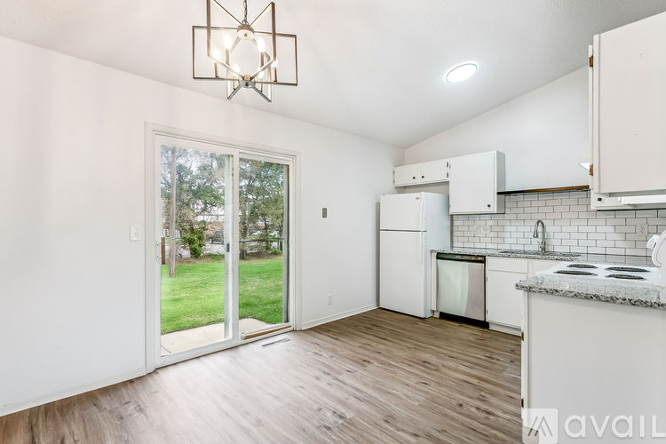 A kitchen with white cabinets and a wooden floor.
