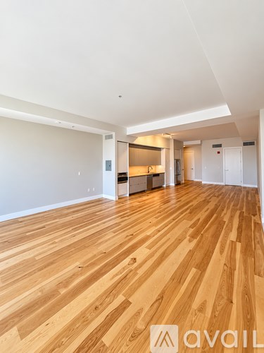A spacious room with wooden flooring and white walls.