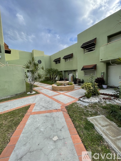 A courtyard with a cross pattern walkway and a small fountain in the middle.