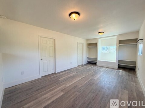 A spacious room with wooden flooring and white walls.