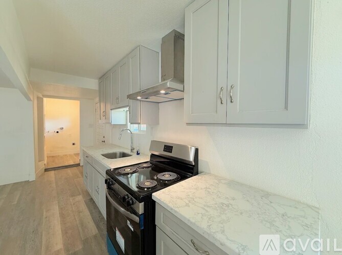 A kitchen with a stove, sink, and cabinets.