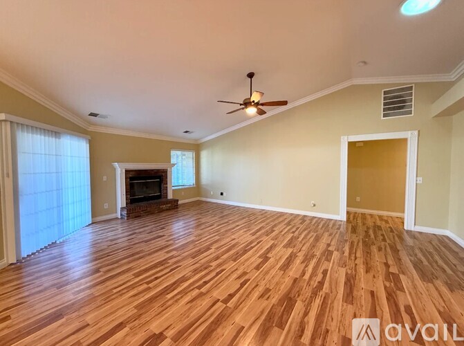 A spacious room with wood flooring and a ceiling fan.