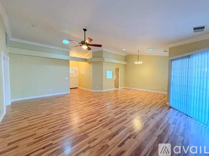 A spacious room with wooden flooring and a ceiling fan.