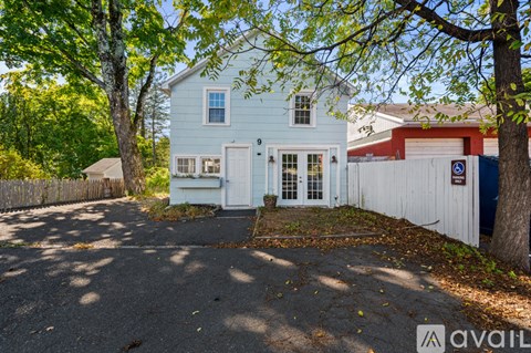A blue house with a white fence and a tree in front.
