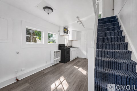 A staircase with a black carpeted runner leads up to a white ceiling.