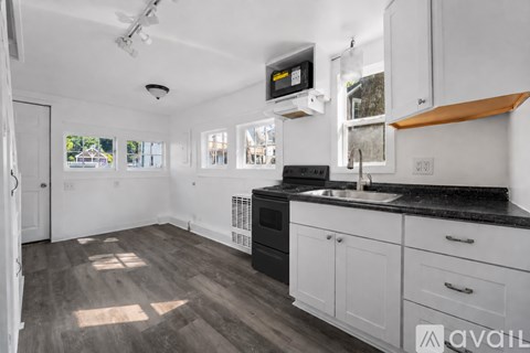 A kitchen with white cabinets and black countertops.
