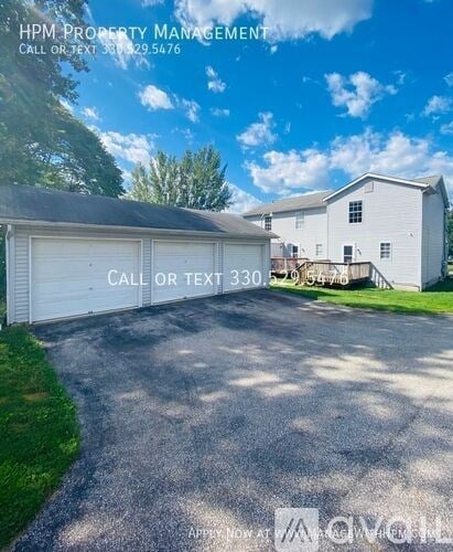 A white garage with a sign that says "HPM PROPERTY MANAGEMENT" and a phone number.