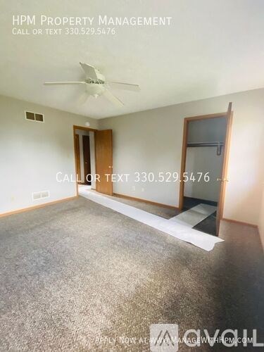 A room with a carpeted floor and a ceiling fan.