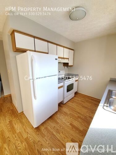 A kitchen with a white fridge and wooden floors.
