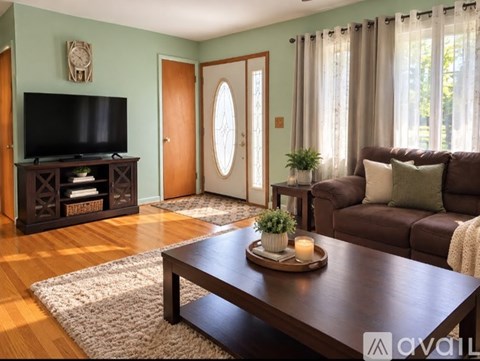 A living room with a brown couch, a wooden coffee table, and a flat screen TV.