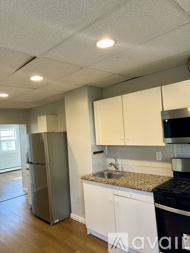 A kitchen with a refrigerator, sink, and stove.