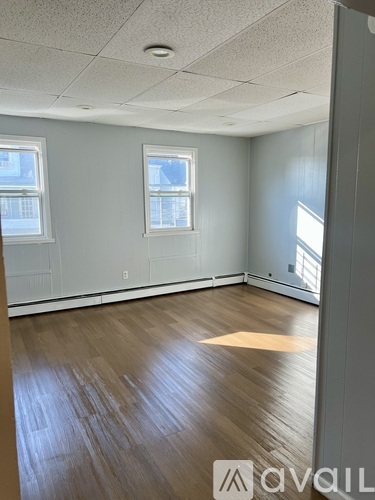 A room with wooden floors and two windows.