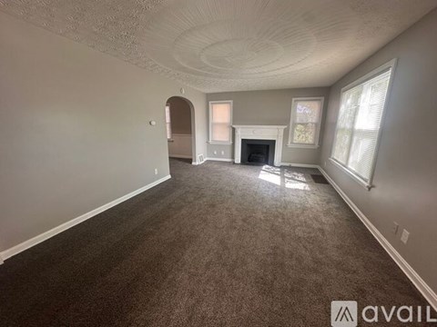A spacious living room with a fireplace and a carpeted floor.