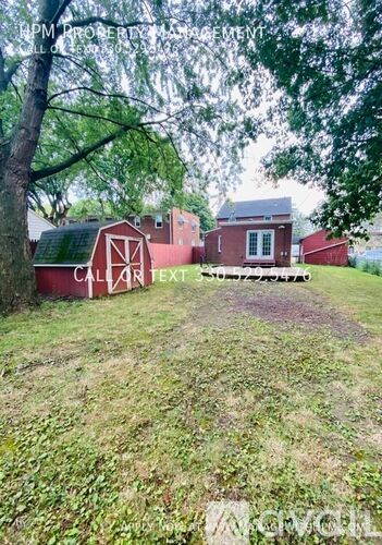 A red barn with a white door and windows sits in a grassy field.