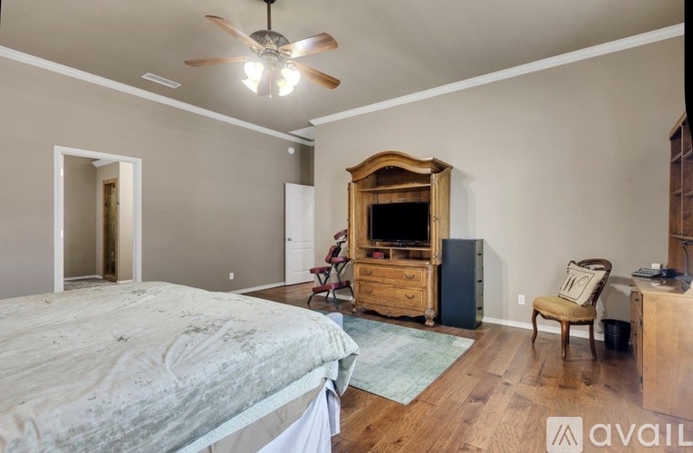 A bedroom with a bed, dresser, chair, and a ceiling fan.