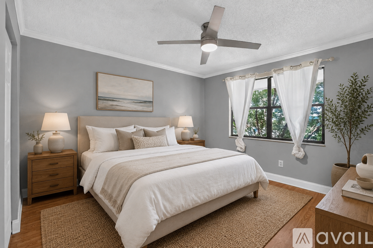 A bedroom with a large bed, two lamps, and a ceiling fan.