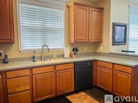 A kitchen with wooden cabinets and a black dishwasher.
