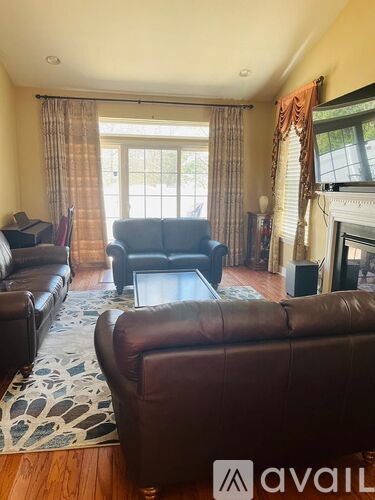 A living room with a brown leather couch and a fireplace.