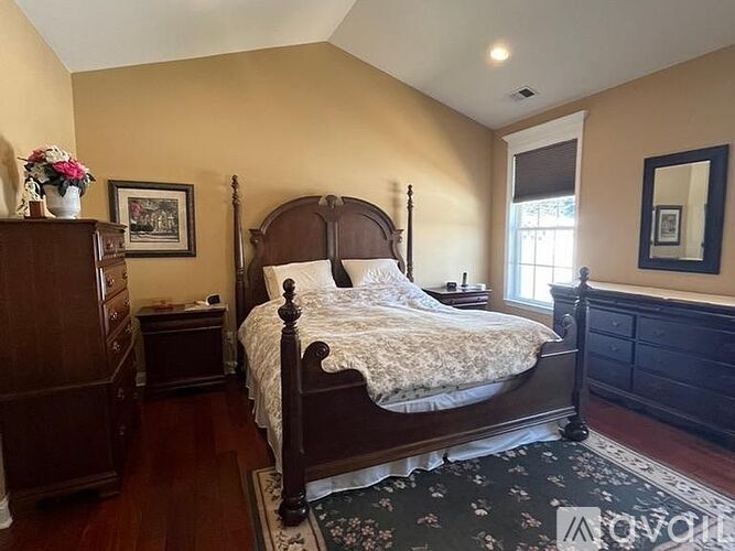 A bedroom with a large bed and a wooden dresser.