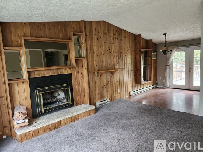 A living room with a fireplace and wooden walls.
