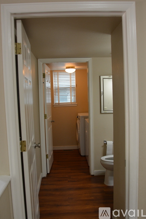 A hallway with a toilet and a window with blinds.