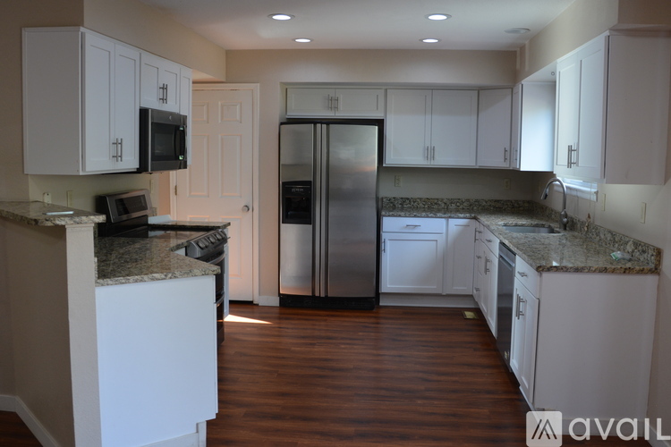 A kitchen with white cabinets and a granite counter top.