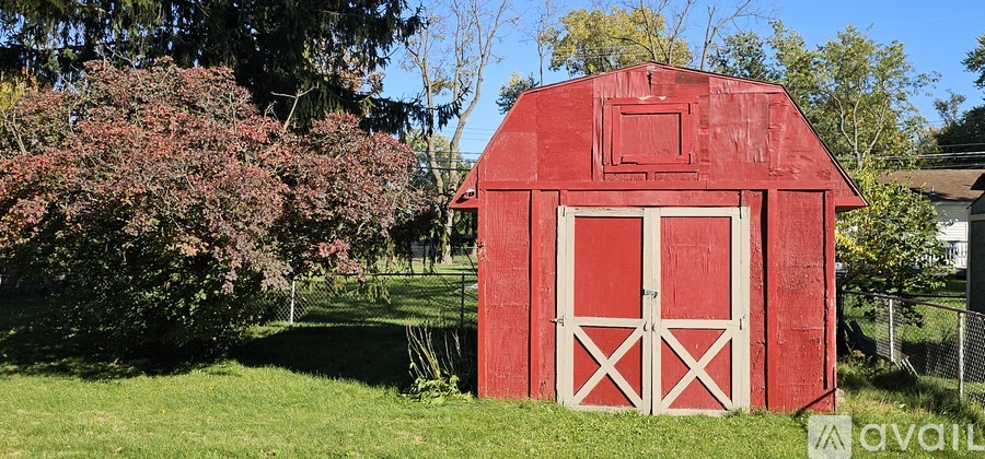 A red barn with white doors stands in a grassy field.