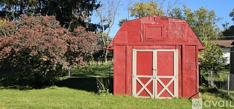 A red barn with white doors stands in a grassy field.