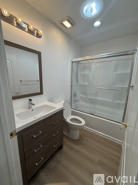 A bathroom with a toilet, sink, mirror, and shower.