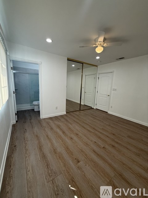 A room with wooden flooring and a ceiling fan.