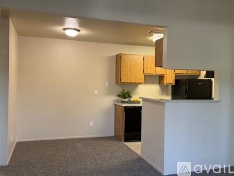 A room with a white wall and a wooden cabinet with a TV on it.