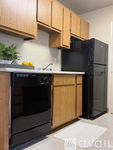 A kitchen with a black refrigerator and wooden cabinets.