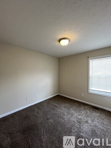 A room with a carpeted floor and a window with blinds.