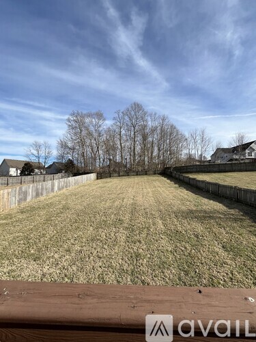 A backyard with a wooden fence and a grassy field.