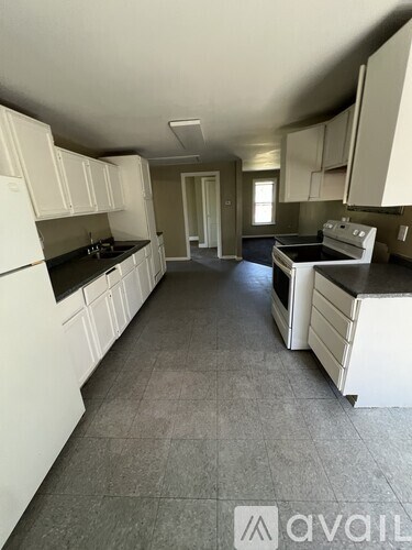 A kitchen with white cabinets and black countertops.